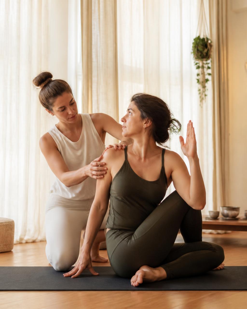 Yoga teacher guiding a private student through a seated twist